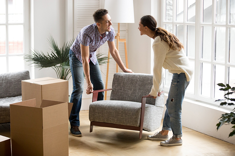 Couple carrying chair together, placing furniture moving in new home